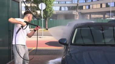 Bir adam araba yıkamada araba yıkar.