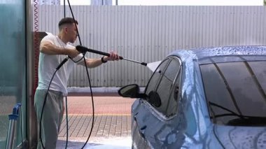 Bir adam araba yıkamada araba yıkar.