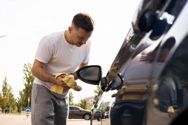 Adamın biri arabasını siliyor.