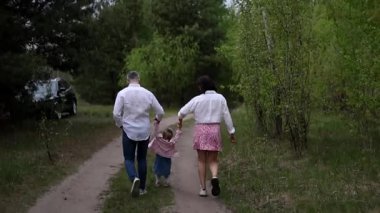 Küçük çocuklu mutlu bir aile parkta eğleniyor.