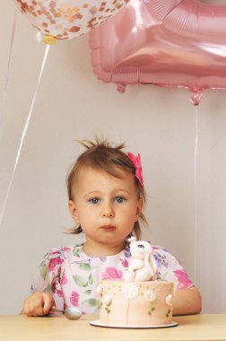 İki yaşında bir kız doğum günü pastası yiyor.