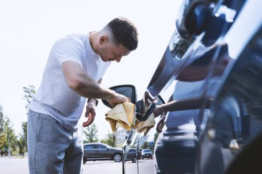 Adamın biri arabasını siliyor.