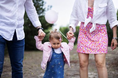 Genç ebeveynler bir çocukla yürüyor.