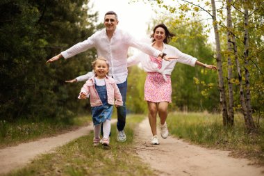 Ebeveynler parkta küçük kızlarıyla oynuyorlar.