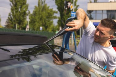 Bir adam araba süpürür.