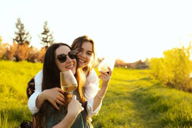 Güzel kızlar gün batımında şarap içiyor.