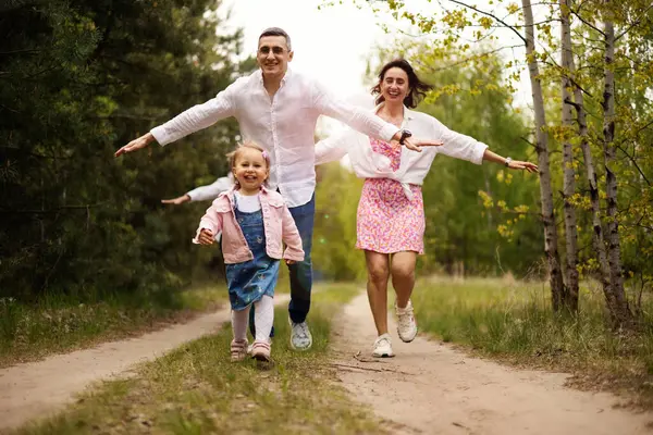 Ebeveynler parkta küçük kızlarıyla oynuyorlar.