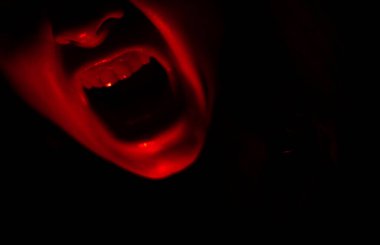 Siyah arka planda korkunç kırmızı ağız.