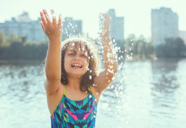 Su sıçramalarıyla oynayan kız çocuğu. Seyahatin keyfi
