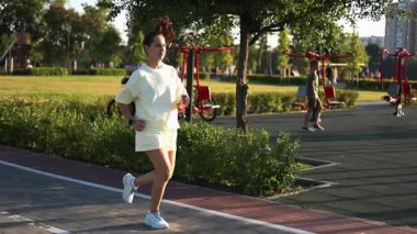 Şehir parkında koşan mutlu bayan koşucu.