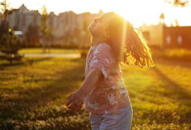 Kız gün batımında parkta koşup oynuyor.