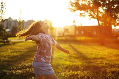 Kız gün batımında parkta koşup oynuyor. 