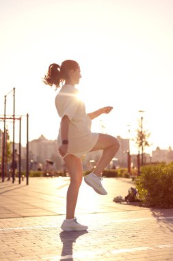 Parkta zıplayan genç bir kadın. 