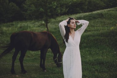 Atın yanında beyaz elbiseli güzel bir manken.