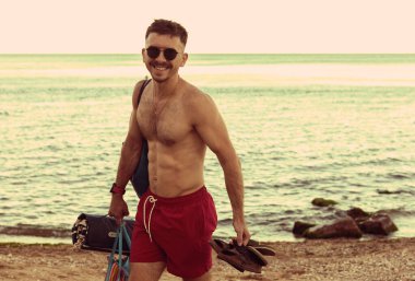 Bir adam tatil sırasında sahil boyunca yürür.