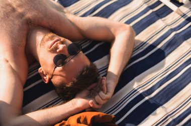 Genç bir adam sahilde dinleniyor.