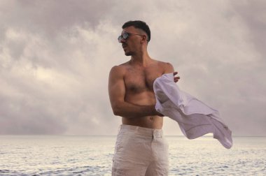 Denize karşı çıplak gövdeli yakışıklı bir adam.