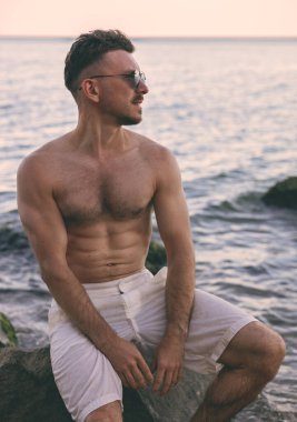 Yakışıklı adam deniz kenarında gün batımını seviyor.