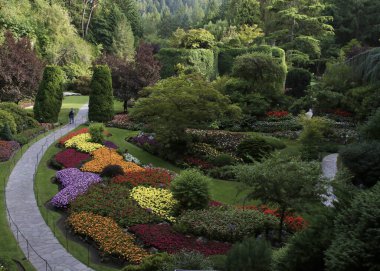 Çiçek açmış resmi bir bahçede yürüyorum.