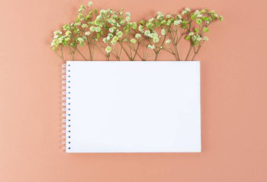 Boş beyaz çarşaf ve açık yeşil çigila çiçekli küçük dallarla dolu not defteri..