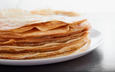 Kahverengi bir masada kızarmış krep ile yuvarlak bir tabak. Kahvaltıda tatlı bir tatlı. Güneşli sabah.