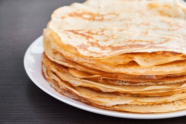 Kahverengi bir masada kızarmış krep ile yuvarlak bir tabak. Kahvaltıda tatlı bir tatlı. Güneşli sabah.