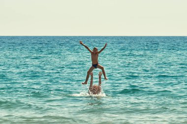 Baba ve Oğul tatilin tadını çıkarıyor. Neşeli baba, mutlu oğul kaldırıyor. Su sıçrıyor. Ebeveynler ve çocuklar yakınlık.