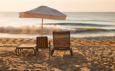 Gün batımında iki sandalye ve bir şemsiyeyle rahatlamak..