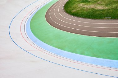 Canlı bir Velodrome pistinin yukarıdan aşağı görüntüsü renkli şeritleri ve kıvrımlı tasarımı sergiliyor. Geometrik desenler ve zıt renkler soyut temalar için görsel olarak çarpıcı bir kompozisyon oluşturur.