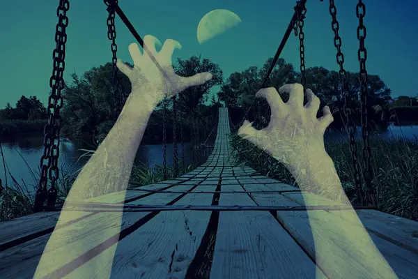 Stock image A ghostly hand reaching out towards an eerie suspension bridge under the moonlight. Haunting atmosphere, combined with the dark landscape, creates a perfect scene for Halloween or horror-themed design