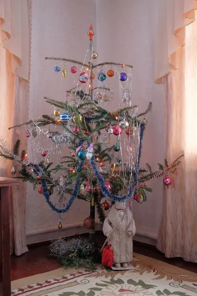 Renkli süsler, süsler ve çelenklerle süslenmiş eski tarz Noel ağacı. Geleneksel bir figür temeli oluşturur, sıcak, klasik bir odada nostaljik bir tatil atmosferi sağlar..