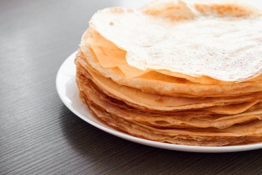 Kahverengi bir masada kızarmış krep ile yuvarlak bir tabak. Kahvaltıda tatlı bir tatlı. Güneşli sabah.