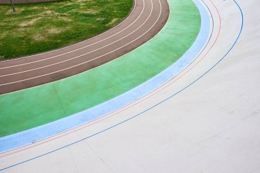 Canlı bir Velodrome pistinin yukarıdan aşağı görüntüsü renkli şeritleri ve kıvrımlı tasarımı sergiliyor. Geometrik desenler ve zıt renkler soyut temalar için görsel olarak çarpıcı bir kompozisyon oluşturur.