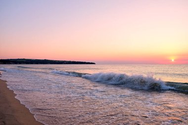 A sunrise over a waves sea and pastel summer beach. clipart