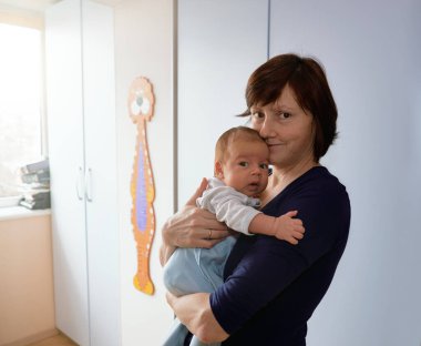 A loving mother holding her newborn baby in a cozy, light-filled nursery. A heartwarming scene symbolizing care, family bonds, and early motherhood. clipart