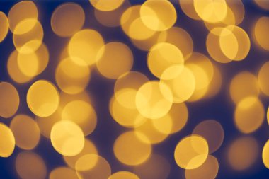 Karanlık Arkaplan Üzerindeki Odaklanmış Turuncu Işıklar. Yumuşak, sıcak bokeh ışıkları rüya gibi ve şenlikli bir ortam yaratıyor. Tatil temaları, kutlamalar ve soyut geçmişler için mükemmel..