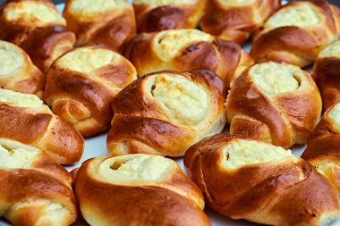 Taze pişmiş, krem peynir dolgulu altın-kahverengi hamur işleri, bir tabağa yakın konumda sergilenmiş, iştah açıcı ayrıntıları ve ev yapımı pişirilmiş ürünlerin dokusunu yakalıyor..