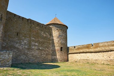 Açık mavi gökyüzünün altında deniz kenarında devasa taş kuleleri olan antik ortaçağ kalesi. İyi korunmuş duvarlar ve mimari sergilenen tarihi miras ve askeri savunma yapıları.