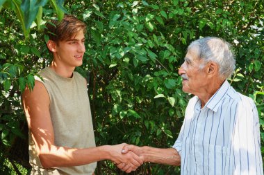 Kıdemli ve genç adam tokalaşıyor. Nesiller arası bağlantı. Büyükbaba ve torun sevgisi.