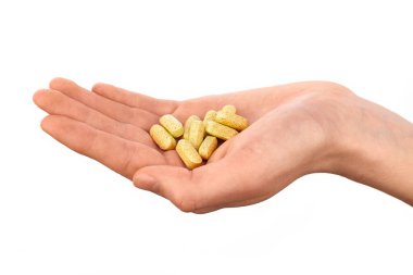 Beyaz arka planda izole edilmiş sarı vitamin hapları döken yakın plan bir el. Sağlık, beslenme takviyeleri ve ilaç konsepti.