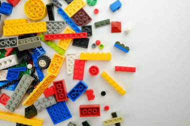 Beyaz arka planda rengarenk plastik yapı taşları. Yaratıcılık, inşaat ve çocuk oyuncakları için parlak ve oyuncu tasarım unsurları.
