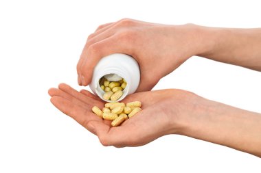 Beyaz plastik bir şişeden sarı vitamin hapları döken yakın plan bir el. Sağlık, beslenme takviyeleri ve ilaç konsepti.