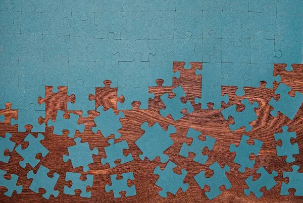 Ahşap yüzeyinde dağınık mavi parçaları olan eksik yapboz. Sorun çözme, takım çalışması, eksik parçalar ve strateji kavramı.