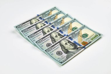 Beyaz arka planda yeni 100 dolarlık banknotlar serpiştirilmiş. Finans, zenginlik, tasarruf, bankacılık veya ekonomik başarı kavramı.