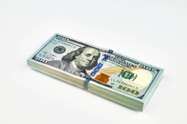 Mavi güvenlik şeritli 100 dolarlık banknotlar yığını, özenle paketlenmiş ve beyaz arka plana yerleştirilmiş, zenginliği, tasarrufu, finansmanı veya bankacılığı simgeliyor..