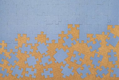 Karton yüzeyde dağınık parçalarla tamamlanmamış mavi yapboz. Problem çözme, takım çalışması, strateji ve yaratıcılık kavramı. Bulmaca çözülüyor, düz görünüm.