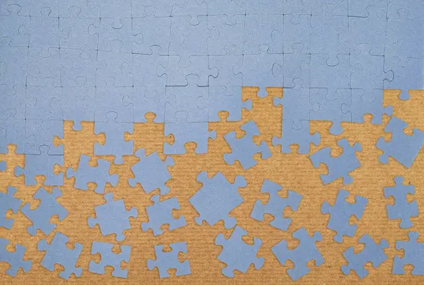 Karton yüzeyde dağınık parçalarla tamamlanmamış mavi yapboz. Problem çözme, takım çalışması, strateji ve yaratıcılık kavramı. Bulmaca çözülüyor, düz görünüm.