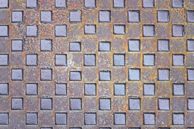 Paslanmış metal kare bir plakaya yakın plan ve tekrar eden elmas desenli. Arkaplan, endüstriyel tasarım veya grunge dokuları için ideal.