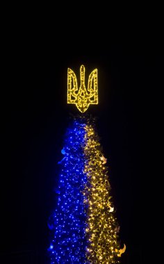 Christmas tree with a trident and decorations in Kyiv, in Ukraine during the war. New year 2023. Glowing trident on a Christmas tree in Kyiv. clipart