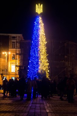 Christmas tree with a trident and decorations in Kyiv, in Ukraine during the war. New year 2023. Glowing trident on a Christmas tree in Kyiv. Monument to Bohdan Khmelnitsy covered from shelling